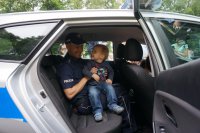 Sierżant Damian Dymanus prezentuje radiowóz chłopcu