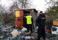 policjanci kontrolują miejsce przebywania bezdomnego drewniany barak